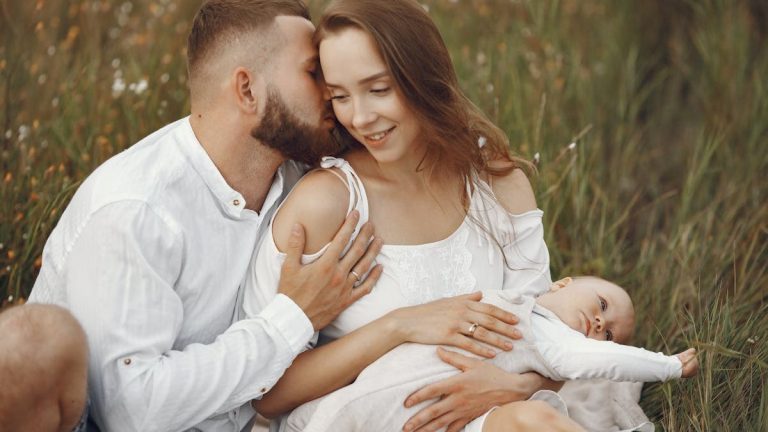 A joyful family enjoying a tender moment outdoors in a lush grassy field.